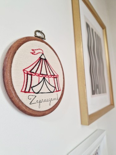 nieduża haftowana ozdoba na ścianę z cyrkiem i napisem Zapraszam!