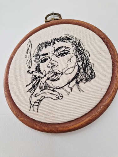 haftowana ozdoba na ścianę przedstawiająca kobietę z papierosem