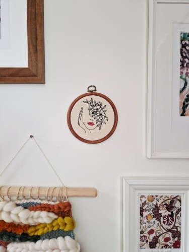 haftowana ozdoba na ścianę z kobietą z kwiatami na głowie